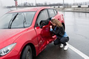 woman stands next to damaged vehicle